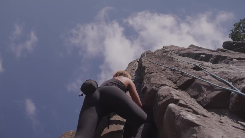 A young woman rock climbs outdoors