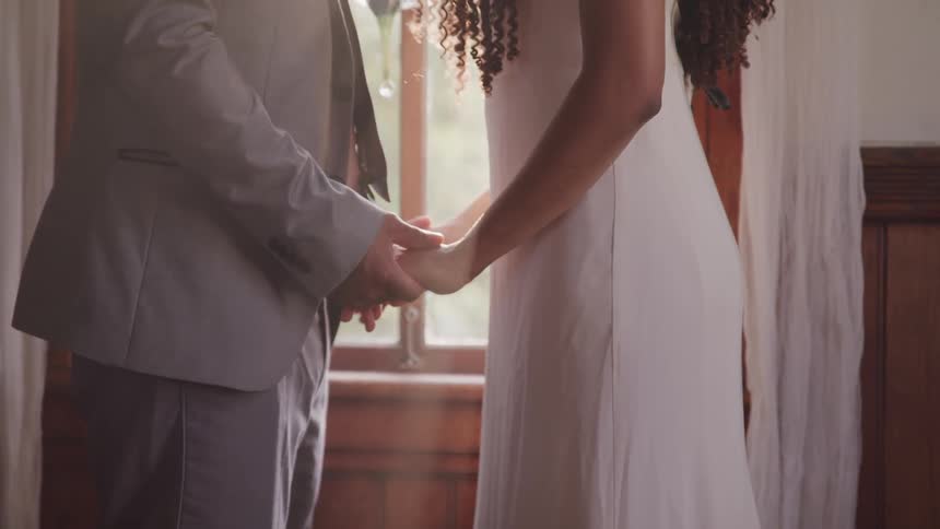 Couple holding hands in front of a window inside house