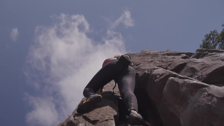 A curly woman climb the cliff