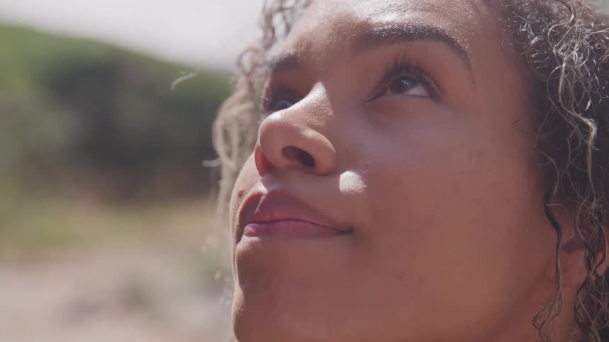 Black curly hair woman looks up during the day