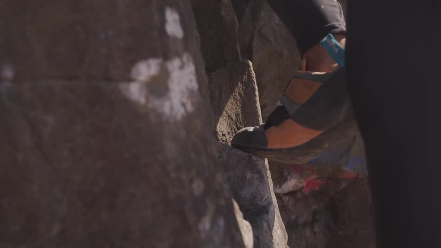 A woman climbing a stone wall