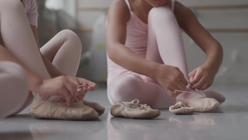 Child ballerinas put on their ballet shoes