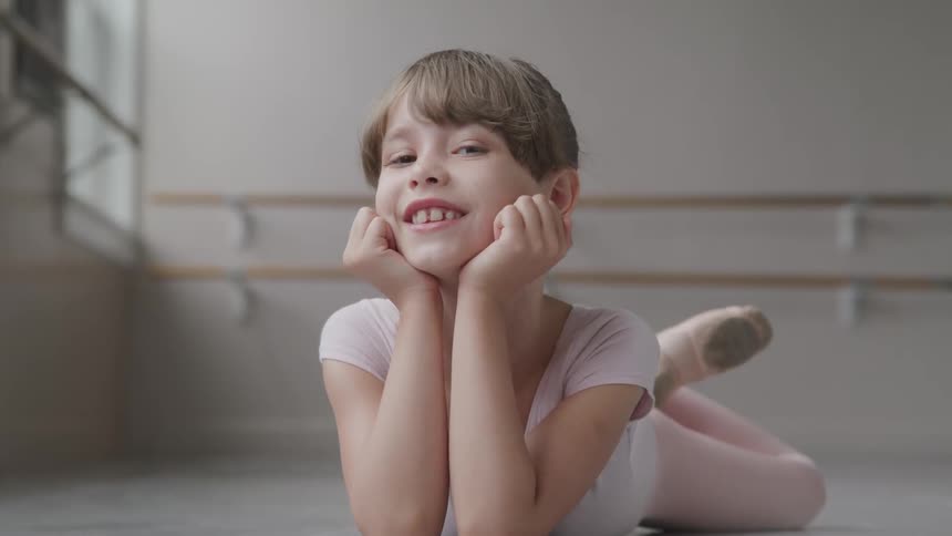 Girl dancer on ballet school smiles at camera