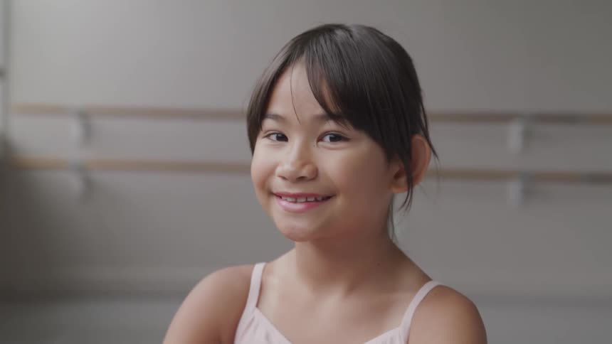 A young ballerina sits and smiles
