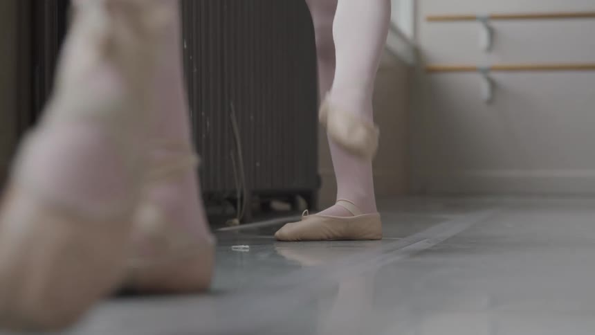 Two young ballerina girls kick their legs in the air