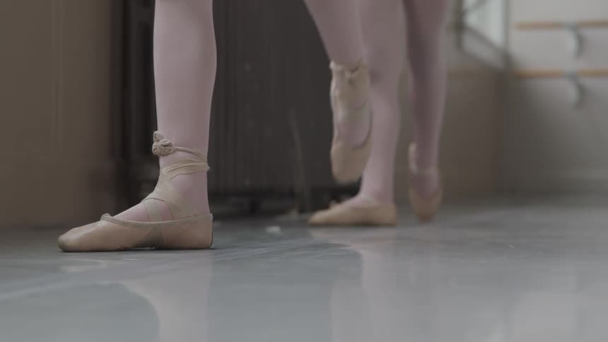 Two little ballerinas holding handrail warms up for dancing in the ballet studio