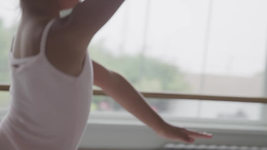 Young ballerina does leap in dance studio during the day