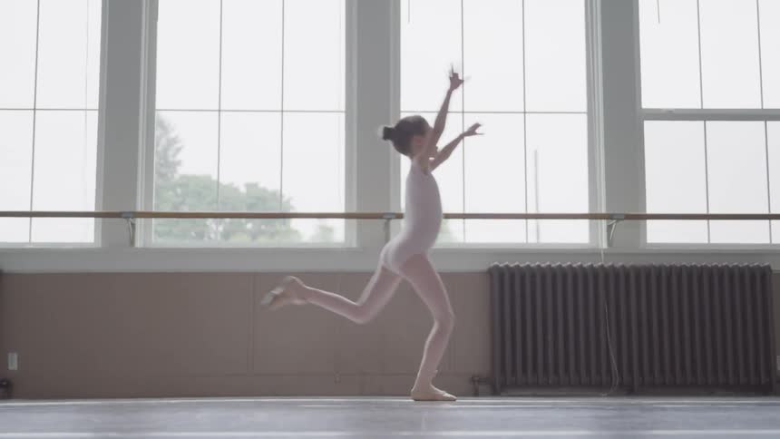A little girl leaps in her dance uniform