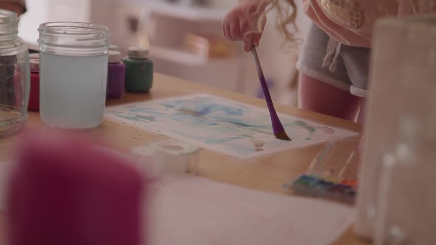 Girl painting with watercolors and brush on paper