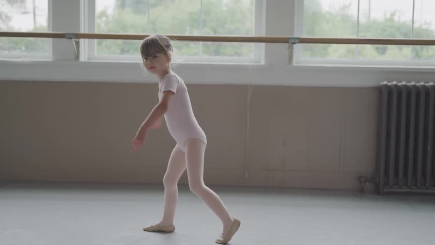 Little ballerina turns around in ballet studio
