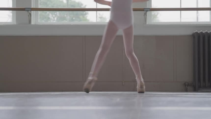 A girl practices ballet spins in a studio