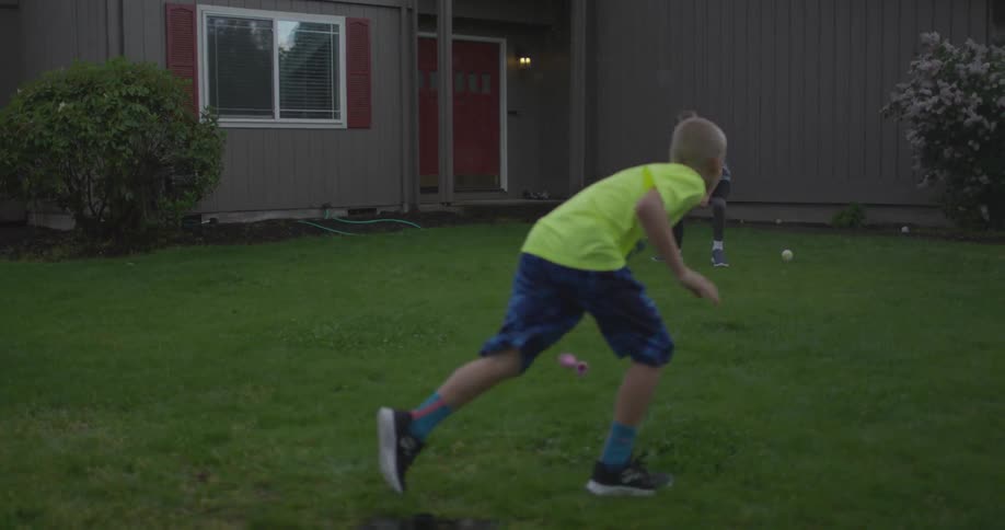 A boy hits a baseball towards another boy