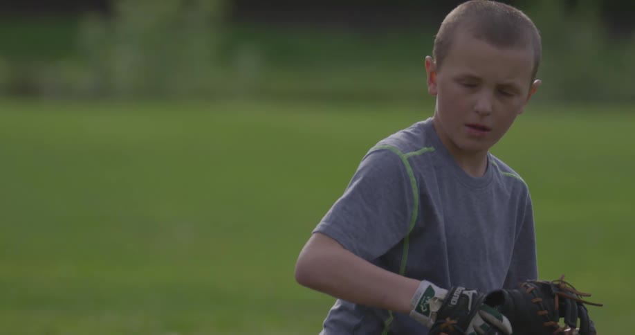 A boy in a gray shirt catches a ball