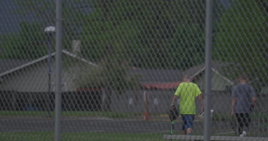Two boys walking away from a fence