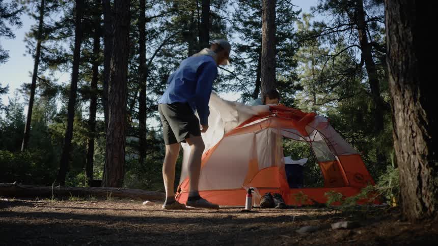 Man and woman dismantle a tent in the forest during the day