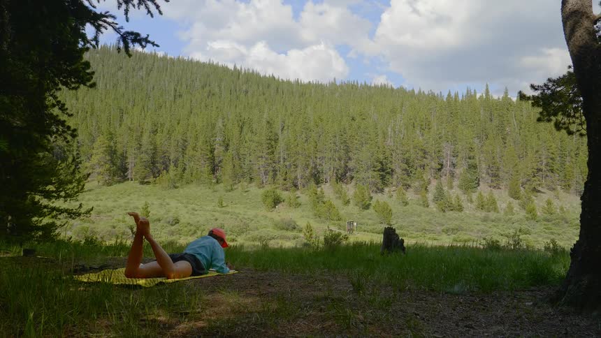 Woman lies on down the ground in the shadow in the forest