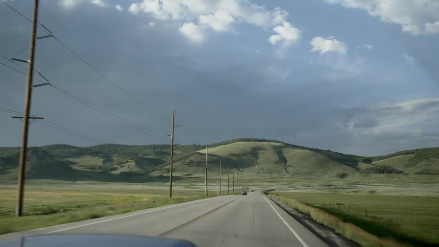 A car drives on a highway leading to hills