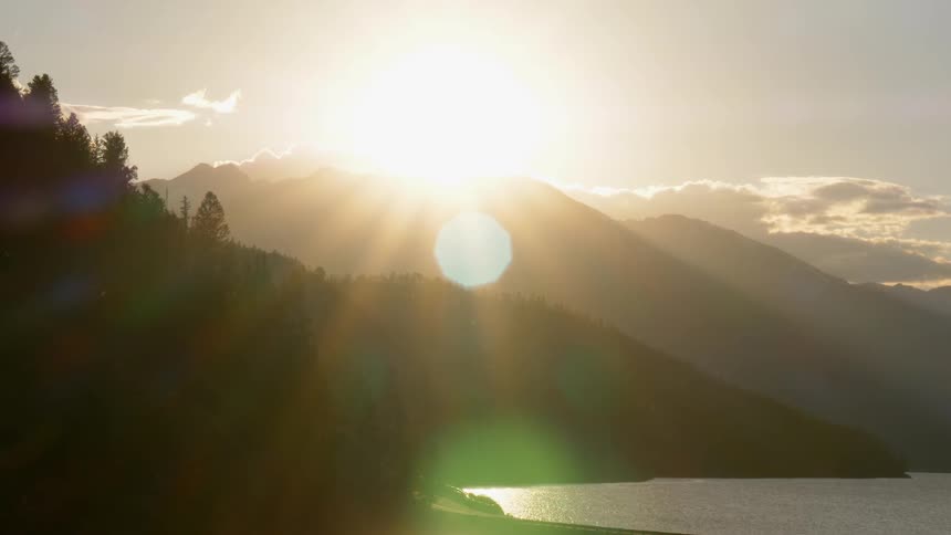 The sun shines brightly from behind a mountain peak