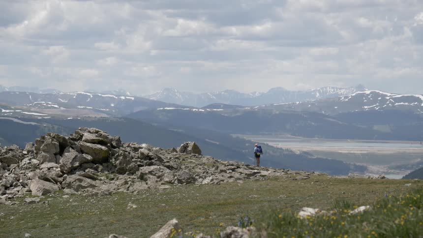 A hiker standing on the edge of a mountain gazing out over the landscape