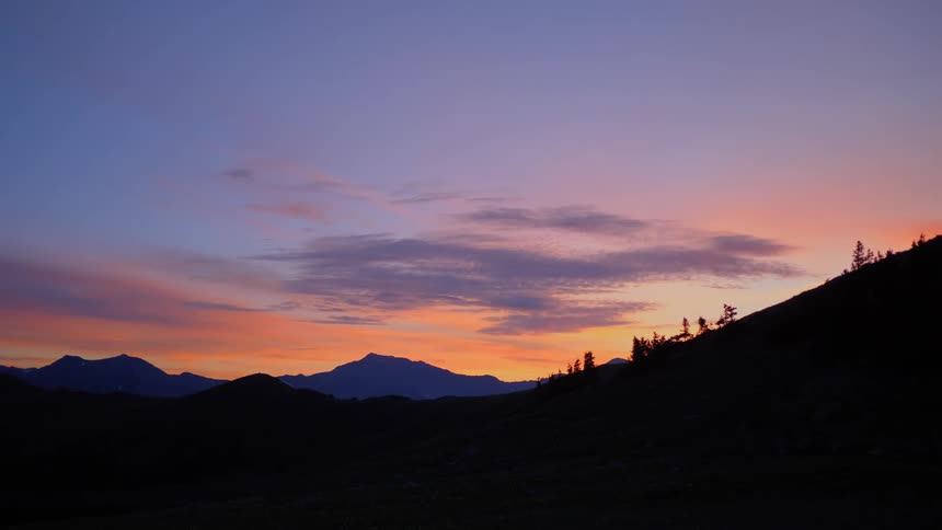 A hilly landscape cloaked in shadow at sunset