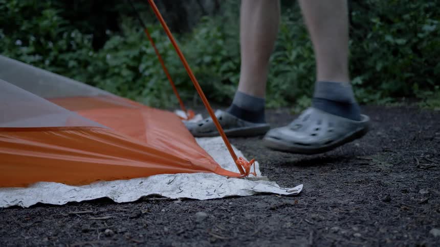 Man dismantles a tent in the woods