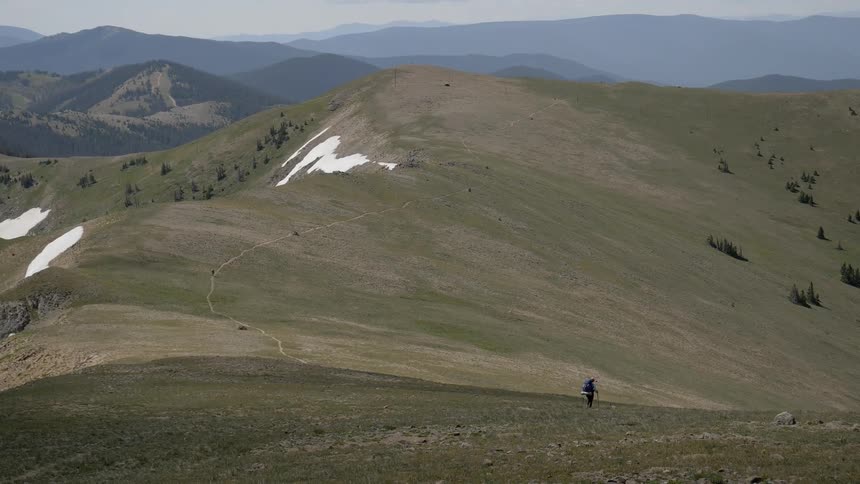 A hiker walks down a hill in winter