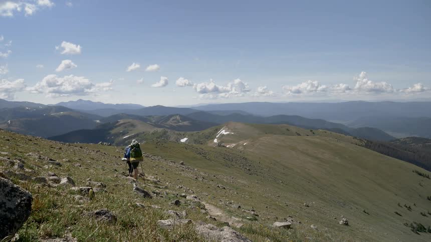 A man and woman hike along a hill top