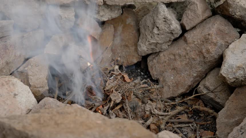 Small fire burns as it is surrounded by rocks