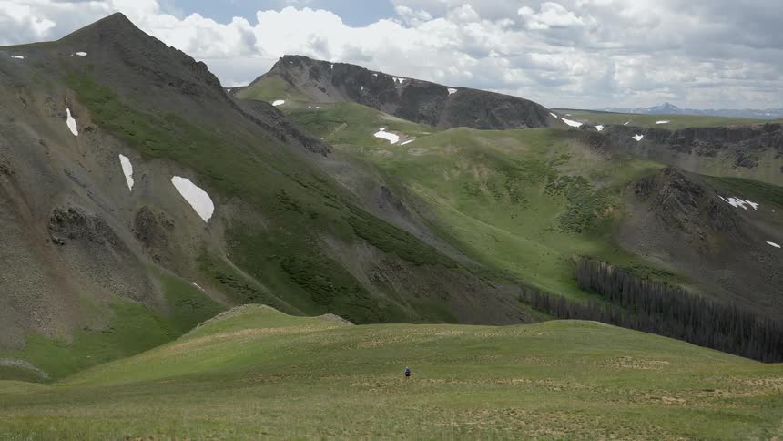 Person walks in a field near the snowy mountains