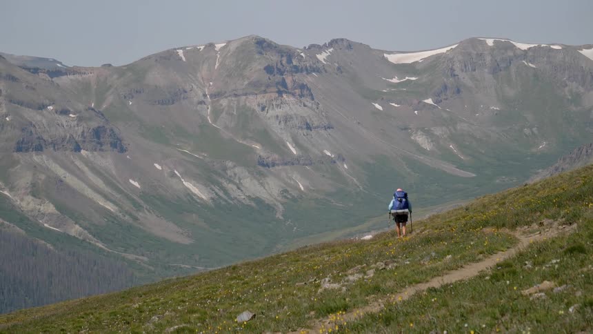 A woman hikes across the side of a hill