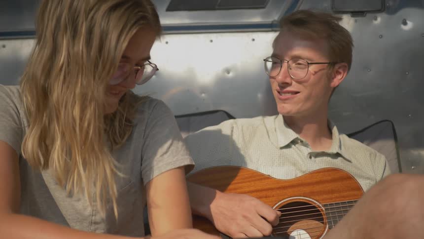 A man plays the guitar and sings a song for a woman