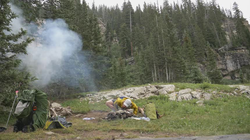 Man lights the campfire in the forest camp