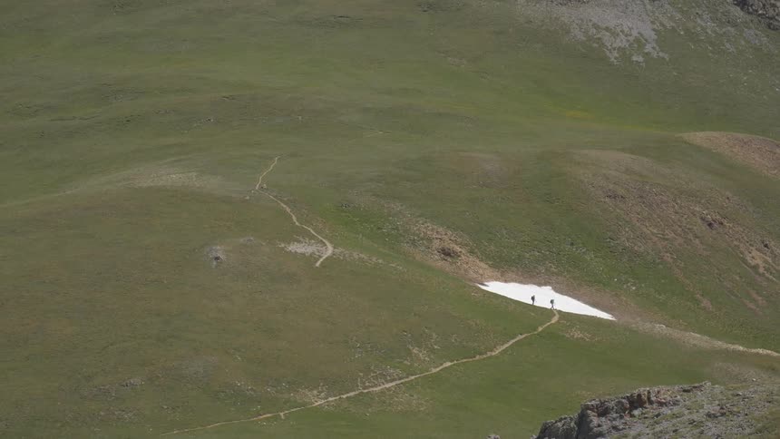 Two people walk down the slope of a small hill