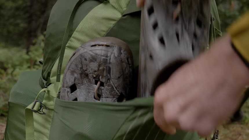 Camper storing shoes on backpack outdoors