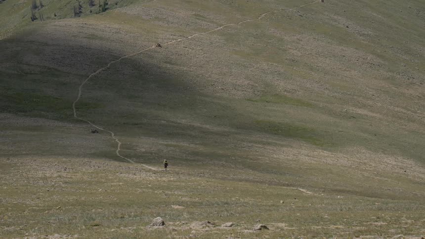 Hiker hiking up a trail on a hill