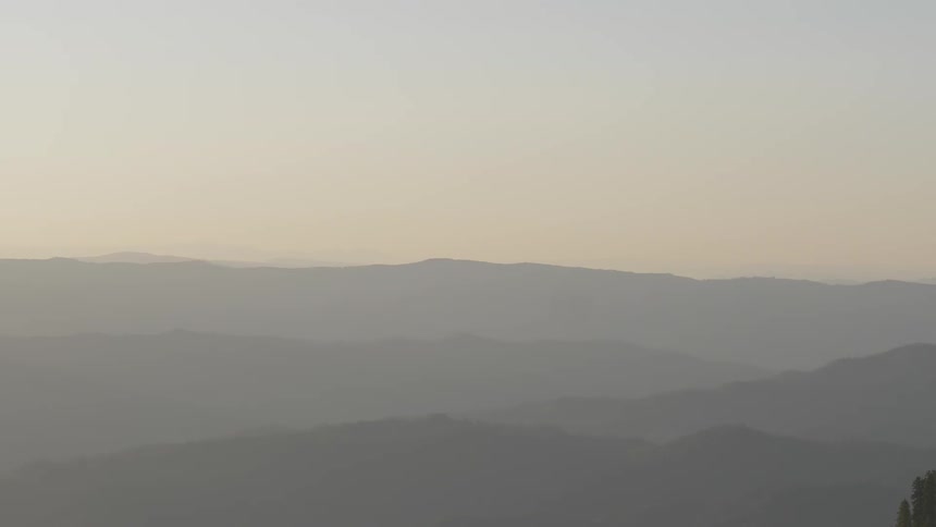 An expansive mountain range is visible in the distance through haze