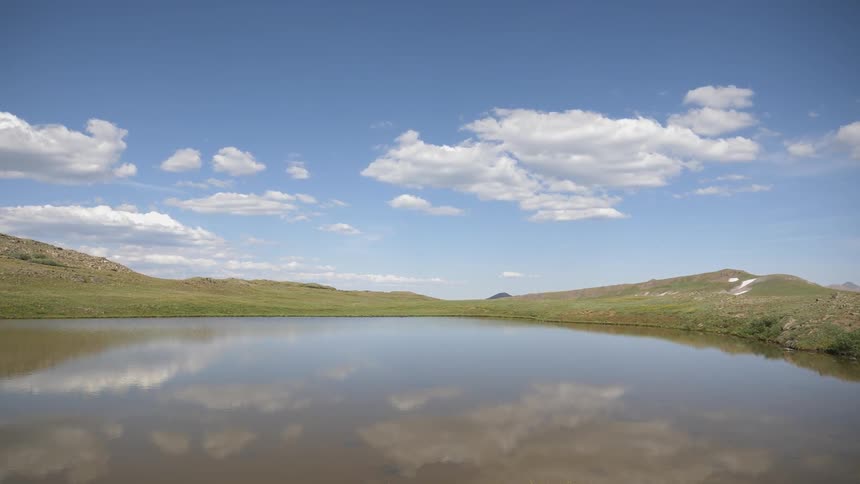 Landscape view of a pond with grasslands behind it