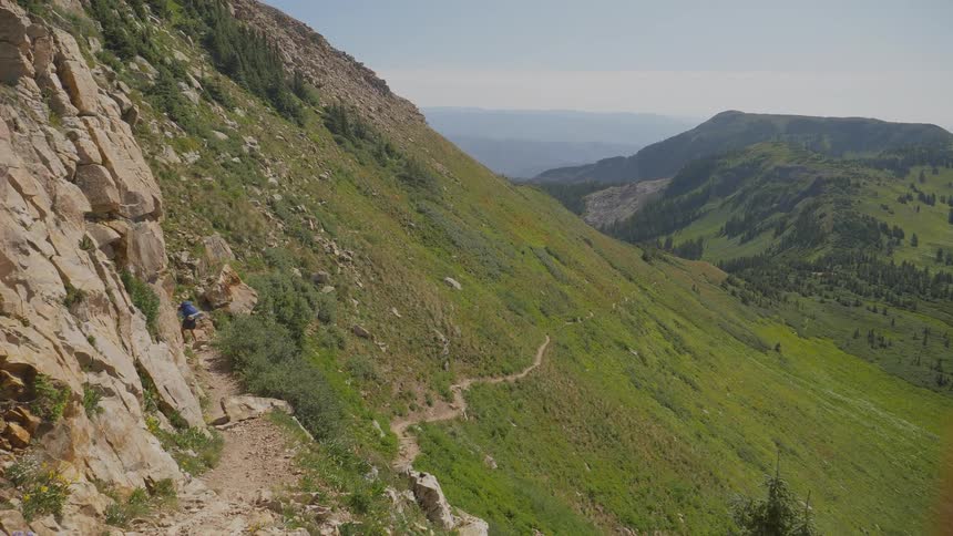 A person walks along a steep and rocky hillside