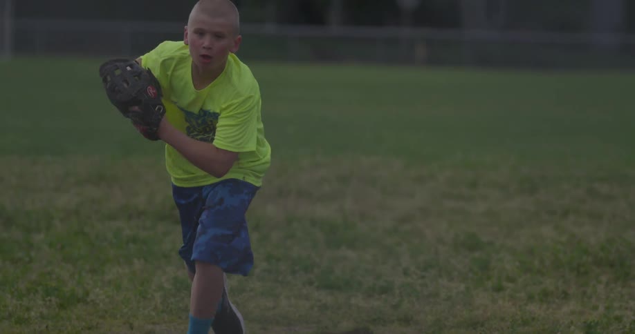 A boy runs over to catch a baseball before throwing it back