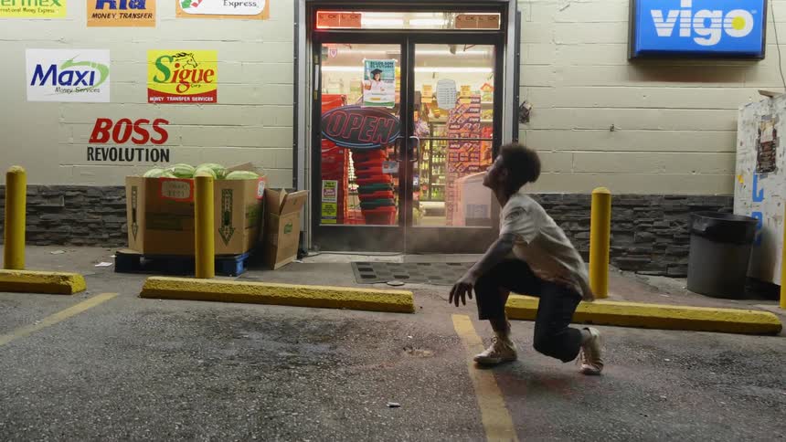 A boy stands up from a parking lot and walks into a store