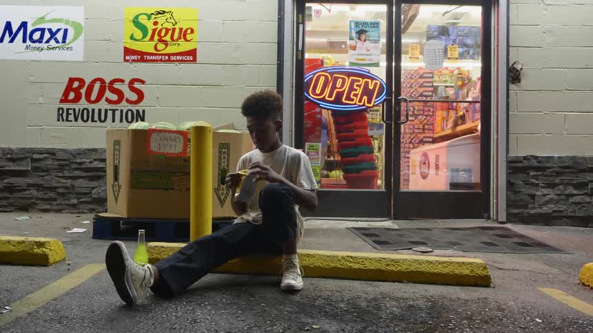 A boy sitting in front of a store