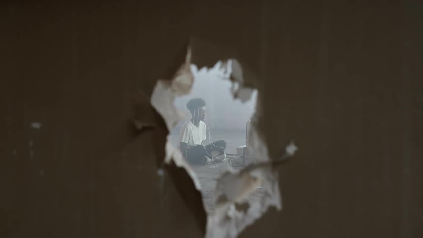 A young boy sits inside and uses electronics