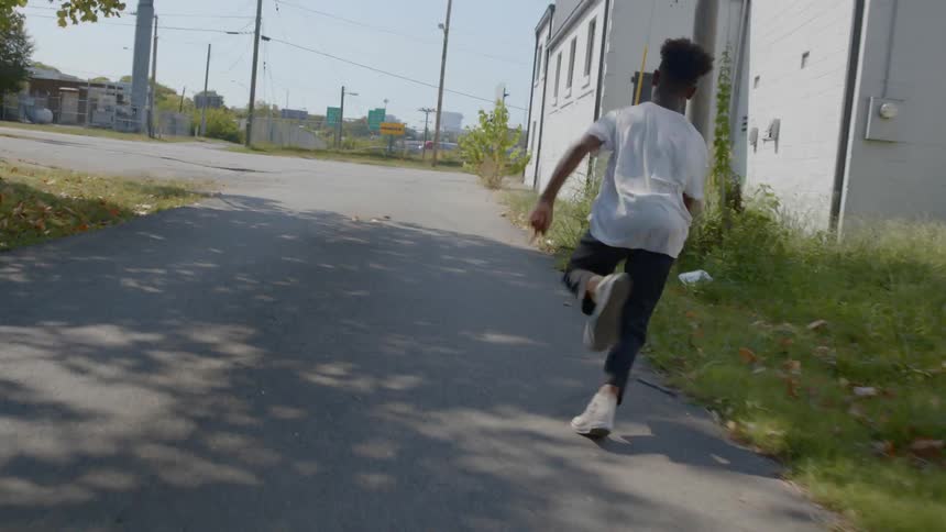 A black child runs out a door and sprints down the road