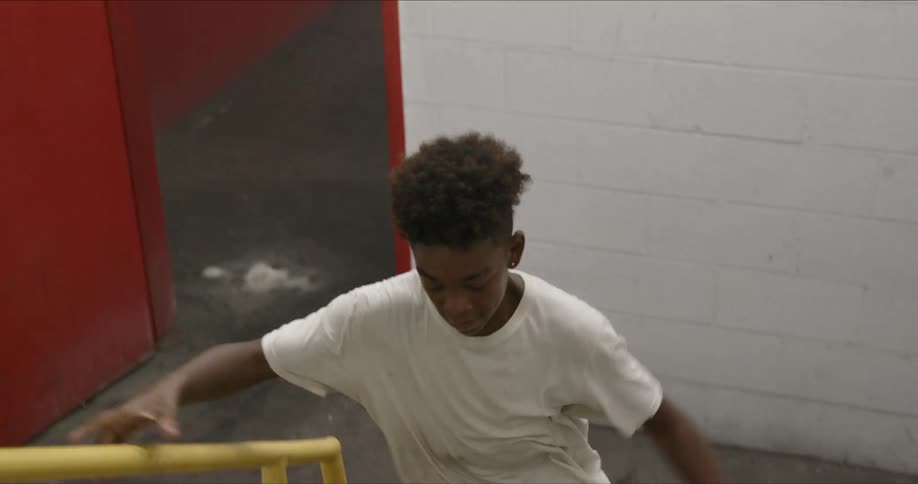 Young boy runs through a red door and up a flight of stairs while holding on to a painted yellow handrail