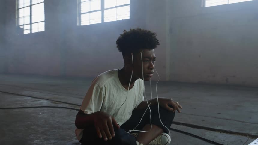 A black boy sitting in front of a monitor
