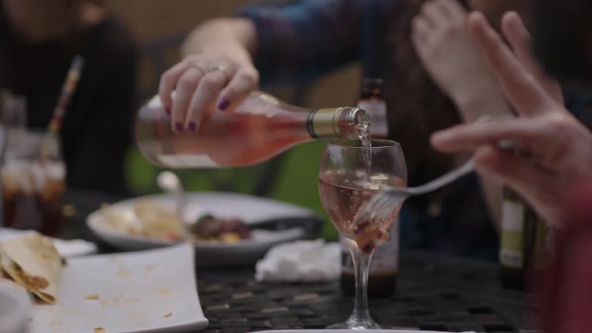 A woman pours wine into a glass