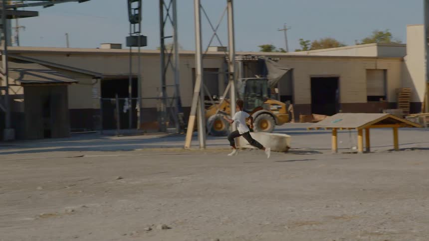 A boy with white shirt running from a warehouse building