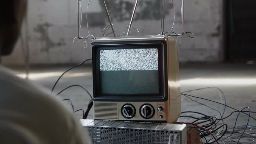 Person watches fuzzy transmission on small television set
