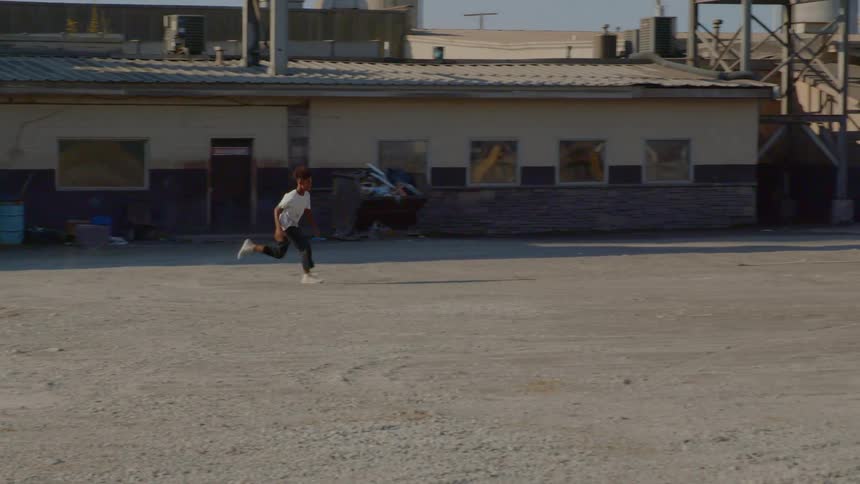 A young boy runs across a dirt lot