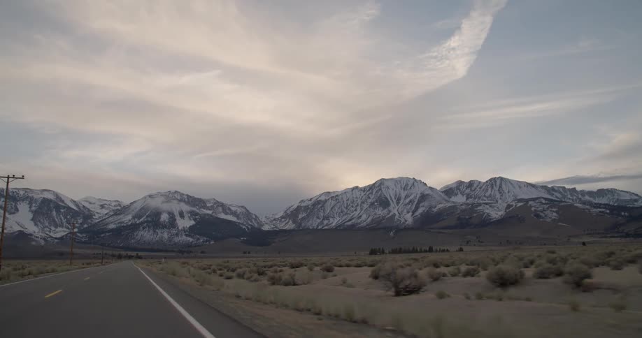 A small road leads to a mountain range on a cloudy day